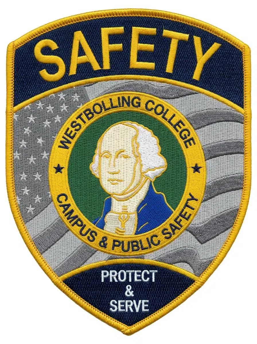 Embroidered navy and gold campus safety shield patch with a gold merrowed border, a gray waving American flag background and a portrait seal in a gold lettered ring