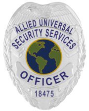 A striking visual of a custom metal badge in silver color, highlighting its ornate design and prominent globe emblem, featuring the words “Allied Universal Security Services” and a reliable safety pin attachment for optimal security.