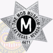 A detailed image of a custom badge featuring a seven-pointed star design, prominently displaying 'THE MOB MUSEUM' in an arc at the top, with 'LAS VEGAS - NEVADA' below and a bold 'M' in the center. The badge is silver with intricate engravings around the edges, highlighting its unique craftsmanship. This visual exemplifies custom badges for police departments with a seven pointed star, showcasing personalization options for various organizations.