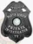 An elegant custom metal badge in black color with a safety pin attachment, featuring the text "DETECTIVE" and "MARTIN BENSON." The badge is adorned with the Texas state seal, representing commitment and expertise in private investigations.