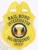 A vibrant image of a custom metal badge in gold color, featuring a shield design with the inscription “Bail Bond Investigator” and “Bail Enforcement,” complete with a central emblem and a safety pin attachment for secure wear.