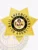 A detailed view of a custom metal badge in gold color, highlighting its ornate star shape and prominent central design that features an emblem, featuring a reliable safety pin attachment for optimal security.