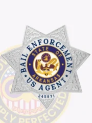 An engaging representation of a custom metal badge in silver color, exhibiting an elegant design with the name “State of Arkansas” in the center and the title “Bail Enforcement US Agent,” designed with a safety pin attachment for effortless integration into attire.