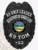 Featuring a polished custom metal badge in black color, this design includes a shield shape with "K9 UNIT LEADER," "DEPARTMENT OF CORRECTIONS," and "K9 TOM" clearly inscribed around a central emblem representing Ohio, along with the number "#22." The badge is completed with a safety pin attachment for easy application on uniforms.