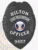 Featuring a custom metal badge in black color, this design highlights the title "HILTON LOSS PREVENTION OFFICER" and includes a decorative emblem at the center. The badge displays the identifier 9857 and is equipped with a safety pin attachment for convenient wear, making it ideal for official use.