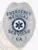 Featuring a detailed custom metal badge in silver color with a secure safety pin attachment, this badge reads "EMERGENCY MEDICAL SERVICES" at the top. The star of life emblem at the center emphasizes its importance in emergency care, reinforcing the commitment of medical technicians to public safety.