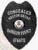 This image displays a polished custom metal badge in black, adorned with decorative elements including the state seal. The inclusion of a safety pin attachment provides a practical option for individuals needing to showcase their identification while maintaining professionalism.