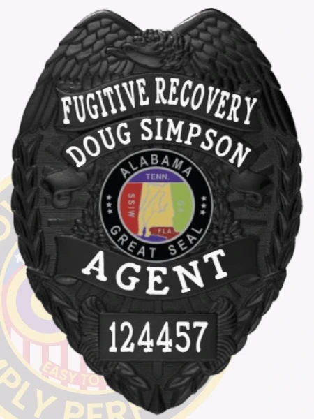 A striking image of a custom metal badge in black color, featuring a detailed shield design adorned with the words “Fugitive Recovery” and the name “Doug Simpson,” complete with a central Alabama seal and a safety pin attachment for secure wear.