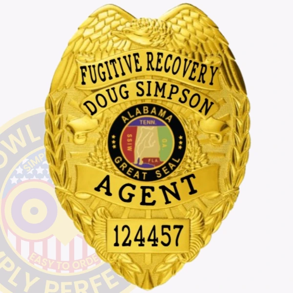 A detailed view of a custom metal badge in gold color, highlighting its ornate design with the inscription “Fugitive Recovery” and a central emblem representing Alabama, featuring a reliable safety pin attachment for optimal security.