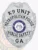 A sleek custom metal badge in silver color shaped like a shield. The badge prominently features "K9 UNIT" and "METROPOLITAN POLICE" at the top, with the center displaying the emblem for the state of Georgia, surrounded by "PUBLIC SAFETY" and "GA." It includes a safety pin attachment for secure fastening on uniforms.
