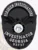 A bold custom metal badge in black color with a safety pin attachment, prominently displaying "FORSHIEM INVESTIGATIONS." The badge features an eagle emblem and the Georgia state seal, emphasizing its professional design and authority for investigators.