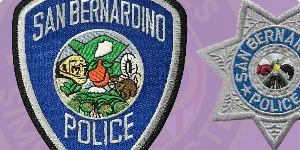 A close-up image featuring two custom embroidered badges: a blue shield badge on the left with 'San Bernardino Police' and detailed colorful designs of local symbols, and a silver star badge on the right labeled 'San Bernardino Police'. This illustration demonstrates how to order custom embroidered badges, emphasizing quality craftsmanship and vibrant detailing.