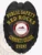 Featuring a polished custom metal badge in black color with a safety pin attachment, this badge reads "PUBLIC SAFETY RED ROCKS." The eye-catching design includes the Red Rocks Community College logo in the center, symbolizing authority and commitment to safety.