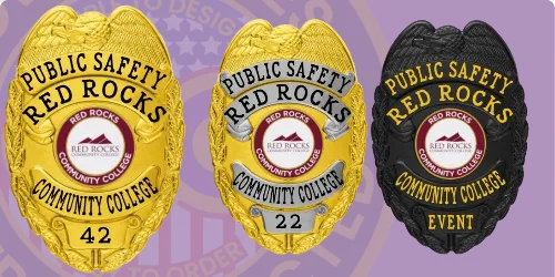Three custom campus safety badges displayed in different finishes: a bright gold badge, a shiny silver badge, and a sleek black badge. Each badge features the title 'Public Safety Red Rocks Community College' with unique identifiers—'42,' '22,' and 'Event' respectively—along with an emblem of the college logo. This image illustrates how to buy custom campus safety badges and university security badges online.