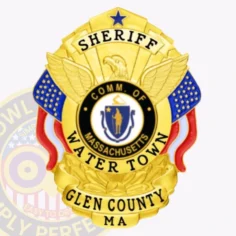 A custom metal badge in gold displaying the title "sheriff" prominently at the top, with a central eagle emblem above the words "comm. Of massachusetts. " the center features a circular state seal, surrounded by the text "water town" and "glen county ma. " the badge is adorned with decorative elements in blue and red, enhancing its vibrant appearance. The polished gold finish emphasizes its official status and significance in law enforcement, showcasing its importance in the community.