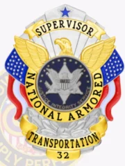 A decorative custom metal badge in silver color adorned with gold panels and a safety pin attachment. This badge includes an eagle motif with the word "SUPERVISOR" prominently displayed, surrounded by "NATIONAL ARMORED TRANSPORTATION." The colorful design blends red, white, and blue elements, enhancing its visual appeal and official representation.