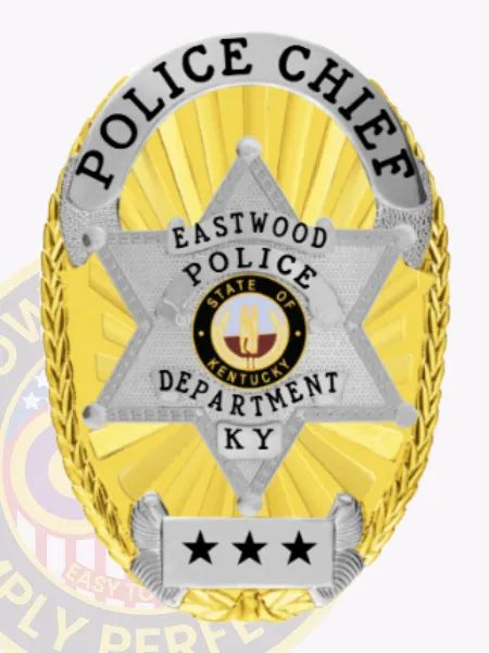 Eastwood police chief custom gold oval metal badge featuring a polished gold background with sunburst texture, highlighted by a silver six-point star containing the colorful Kentucky state emblem, silver scroll with black text POLICE CHIEF across the top edge, EASTWOOD POLICE DEPARTMENT inscribed inside the star, and three black stars on a silver plate near the bottom; safety pin attached.