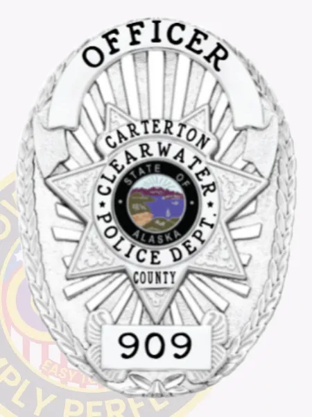 Detailed silver oval police badge for Clearwater Officer in Carterton County highlighting a star emblem with the Alaska state seal in the center, framed by text "CARTERTON CLEARWATER POLICE DEPT. COUNTY," topped with "OFFICER," and displaying the badge number "909" at the bottom, designed with a safety pin attachment.