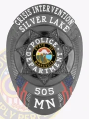 Black custom oval metal badge for Silver Lake Police crisis intervention unit, showing a raised 7-point star centered around the State of Minnesota seal, white lettering for "CRISIS INTERVENTION," "SILVER LAKE," "POLICE DEPARTMENT," and badge number "505 MN," with red, white, and blue flag designs and safety pin attachment.