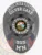 Black custom oval metal badge for Silver Lake Police crisis intervention unit, showing a raised 7-point star centered around the State of Minnesota seal, white lettering for "CRISIS INTERVENTION," "SILVER LAKE," "POLICE DEPARTMENT," and badge number "505 MN," with red, white, and blue flag designs and safety pin attachment.
