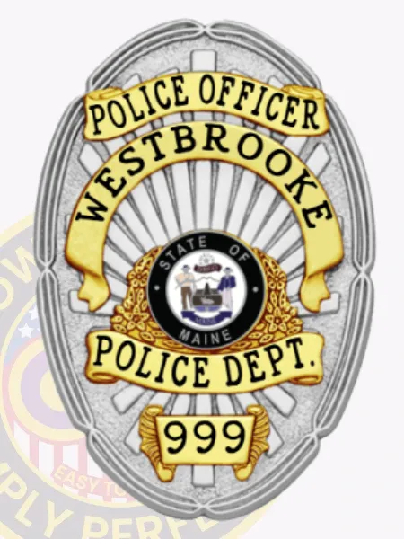 Silver oval custom metal badge for Westbrooke police officer, displaying a polished silver sunburst background behind a black and gold State of Maine seal, with gold banners stating POLICE OFFICER, WESTBROOKE, POLICE DEPT., and a number 999 on a gold plaque at the bottom, featuring a safety pin fastening.