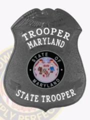 A sleek custom badge in black, designed in the shape of a shield. The top displays the word "TROOPER" followed by "MARYLAND," while the bottom reads "STATE TROOPER." The central emblem features the state seal of Maryland, depicted within a black circle and including images of two soldiers against a vibrant backdrop. The matte finish adds a touch of sophistication, making this custom badge in black an emblem of authority and service.