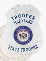 A shiny custom badge in silver, shaped like a shield, featuring the word "TROOPER" at the top and "STATE TROOPER" at the bottom. The center showcases the state seal of Maryland, which includes images of two soldiers and an ornate border. The badge is designed for law enforcement, emphasizing professionalism and authority. The reflective surface enhances its visual appeal, making it an ideal representation of a custom badge in silver.