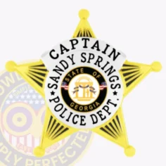Metal gold 5 point star badge for sandy springs police captain, including a white circle banner with "captain sandy springs police dept. " and central georgia state seal, attached by safety pin for secure fit.