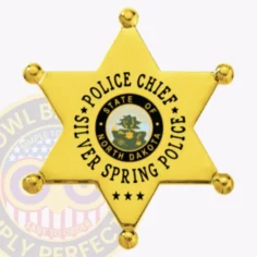 Custom gold metal badge in a 6 point star shape for silver spring police chief, with smooth star points and ball-shaped tips, a central blue and gold north dakota seal, bold black letters around it spelling "police chief silver spring police," and the initials "nd" at the bottom, attached by safety pin.