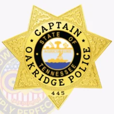 Custom gold 7 point star metal badge for oakridge police captain, showing detailed engraved patterns on each star arm, black text reading "captain," "oakridge police," and badge number "445" around the tennessee state seal at the center, designed with a safety pin attachment.