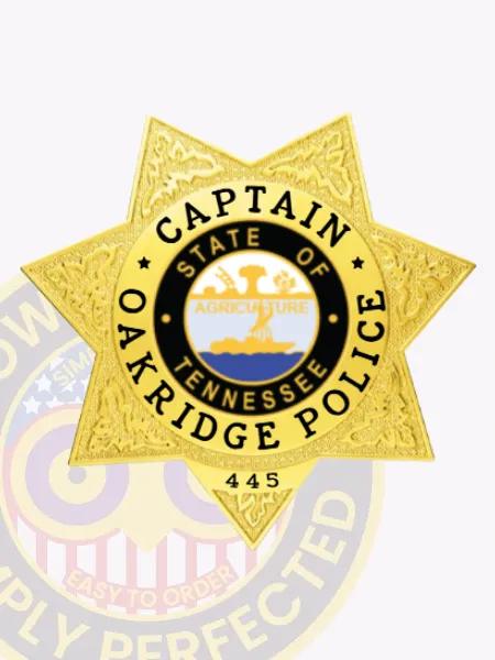Gold custom 7 point star metal badge for Oakridge Police Captain, featuring textured ornamental designs on the star surface, clear black lettering stating "CAPTAIN," "OAKRIDGE POLICE," and identification number "445," finished with a safety pin clasp.