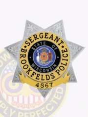 Custom silver metal badge in a 7 point star shape for Brookfields Police Sergeant, decorated with ornate floral embossing on points, a central circle with Wisconsin’s state seal, surrounded by "SERGEANT BROOKFIELDS POLICE" in black letters on a gold band, with a safety pin backing.