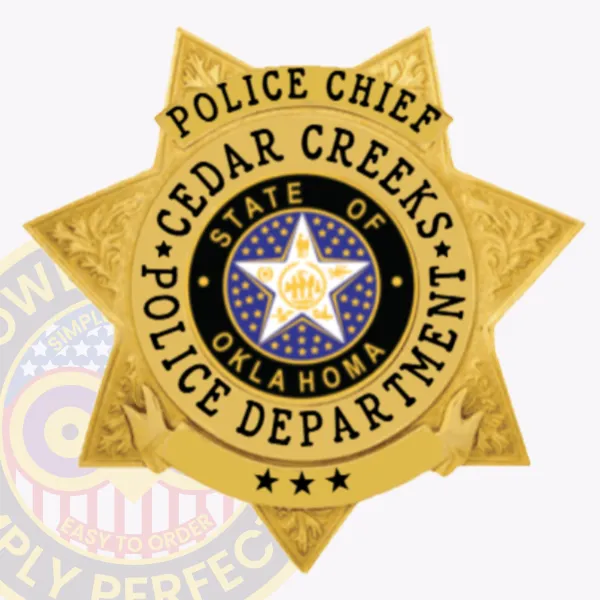 Gold 7 point star police badge for Cedar Creeks Police Chief, decorated with intricate leaf patterns on the star points, a central medallion displaying the Oklahoma state seal and white star, black text surrounding it that says "POLICE CHIEF CEDAR CREKS POLICE DEPARTMENT," and secured with a safety pin.