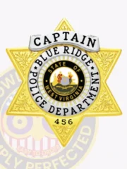 Polished gold 6 point star badge for Blue Ridge Police Captain, highlighting a white banner with black lettering for rank, a colorful West Virginia state seal centered within a ring of department text, ornate leaf motifs on the star surface, and a safety pin fastening on the reverse.