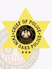 Polished gold six-point star badge custom-made for Twin Oaks Police Chief of Police, highlighting the Louisiana state seal at the center with clear black text around it, accented by three black stars below, attached with a safety pin for secure wear.