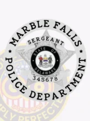 Silver metal badge shaped in a circle with a five-point star at the center, overlaid by the word "Sergeant" on a banner, encircled by the words "Marble Falls Police Department" and the State of Delaware seal, attached by safety pin.