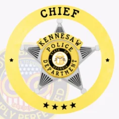 Gold circle banner with bold black letters "chief" and "kennesaw police department," surrounding a silver five-point star badge with the state of georgia emblem in the center, designed with a safety pin fastener.
