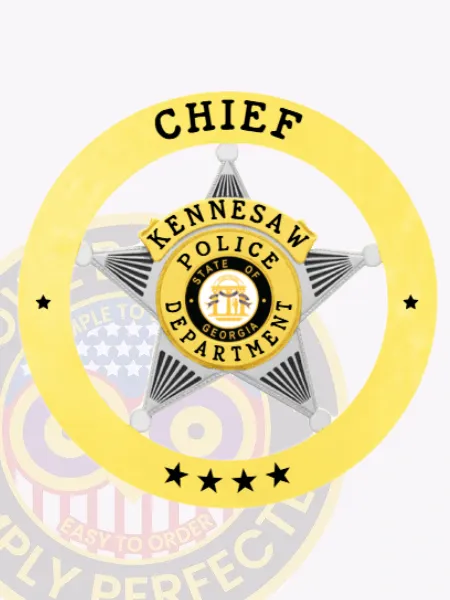 Silver star-shaped badge set within a bright gold ring that reads "Chief" at the top and "Kennesaw Police Department" around the star, with four stars beneath, and the State of Georgia seal prominently displayed in the middle, attached via safety pin.