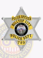 Custom Hilltop City police officer badge in silver metal shaped as a six-point star, with yellow banners reading "POLICE OFFICER," "HILLTOP CITY," and "POLICE DEPT.," positioned around a vivid State of Iowa insignia, equipped with a safety pin attachment.
