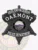 Oakmont police drug enforcement badge in a black 6 point star metal design, displaying white text including "DRUG ENFORCEMENT" at the top, "OAKMONT" prominently in the center, a colorful Colorado state emblem in the middle, and "POLICE DEPARTMENT" along the bottom, secured by a safety pin fastener.