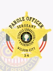 Detailed view of a custom metal badge in gold color with safety pin attachment, shaped like a star. The badge states "PAROLE OFFICER SERGEANT" across the top, with a central depiction of the Washington state seal. Surrounding this emblem are the words "JUVENILE CORRECTIONS WASHINGTON," along with "WILSON CITY 24" at the base, reinforcing its official designation.