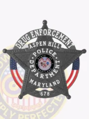 Five-point star badge in black metal for Aspen Hill Police Drug Enforcement, showing detailed white lettering in a circle banner and Maryland seal in the center, finished with a safety pin attachment.
