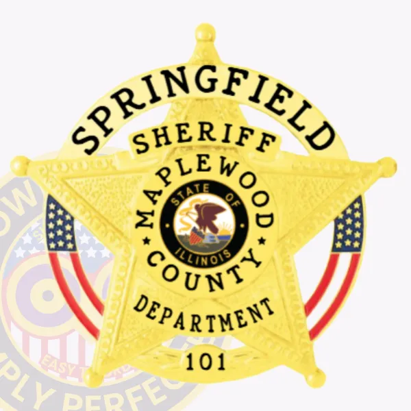 Close up of a custom metal badge in gold color with safety pin attachment, designed in the shape of a star. The badge features "SPRINGFIELD," "SHERIFF," "MAPLEWOOD COUNTY," and "DEPARTMENT" in bold black letters around the edge. In the center, it showcases the state emblem of Illinois, highlighting a detailed depiction of the state seal, along with decorative red and blue stripes, creating an official and polished appearance suitable for law enforcement use.
