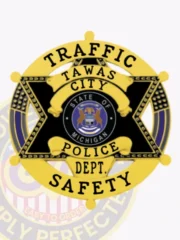 Tawas City Police Traffic Safety badge in black metal shaped as a six-point star, with a gold circle banner reading "Traffic Safety," the Michigan state seal in the middle, and secured with a safety pin.