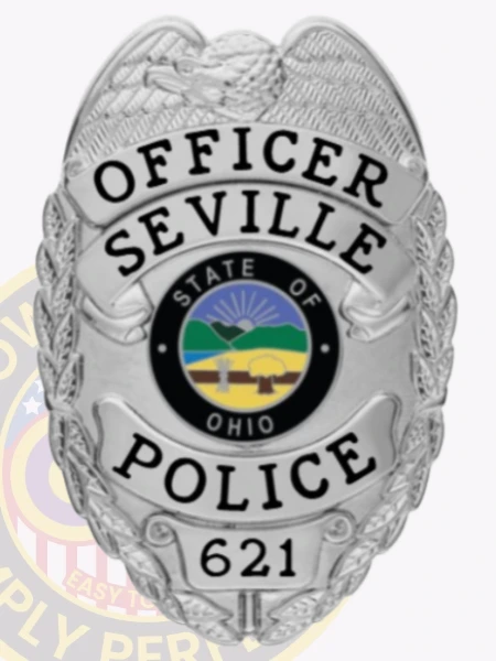 A shiny custom metal badge in silver, designed in the shape of a shield with intricate detailing. The badge features the word "OFFICER" at the top and "SEVILLE POLICE" prominently displayed below in bold black letters. In the center, the state seal of Ohio is visible, showcasing a rising sun over a scenic landscape encircled by a black ring. The badge also includes the number "621" at the bottom. The reflective surface of this custom metal badge in silver enhances its professional appearance, symbolizing authority and dedication in law enforcement.