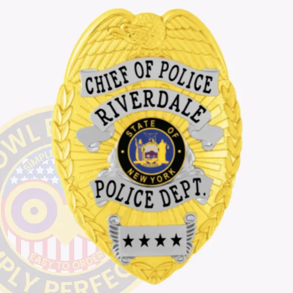 Metal badge in gold for Riverdale Police Chief of Police, highlighting an eagle motif atop the shield, silver ribbon banners with bold black text reading "CHIEF OF POLICE," "RIVERDALE," and "POLICE DEPT.," surrounding the official New York State insignia, finished with four black stars on a silver lower banner and attached by safety pin.