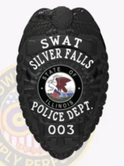 This image illustrates a custom metal badge in black color, prominently featuring "SWAT Silver Falls Police Dept." The badge’s intricate design includes a central state emblem and is fitted with a safety pin attachment for effortless fastening.