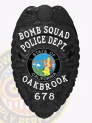 Oakbrook Police Bomb Squad custom black metal badge displaying an eagle emblem on top, bold white lettering around the California state seal, labeled “BOMB SQUAD POLICE DEPT. OAKBROOK,” with badge number “678” and safety pin fastener.