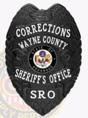 A custom metal badge in a sleek black color, shaped like a shield, representing the Wayne County Sheriff's Office for Corrections. The badge prominently displays "CORRECTIONS" at the top and "WAYNE COUNTY" below it in bold white letters. In the center, it features the state seal of Arkansas, surrounded by decorative elements. The badge also reads "SHERIFF'S OFFICE" and "SRO" at the bottom in white text, and includes a safety pin attachment on the back, allowing for secure wear by school resource officers, emphasizing its functional design and authority.