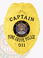 This image highlights a distinguished custom metal badge in silver, marked with "CAPTAIN" and adorned with the Michigan state seal. The badge also reads "PINE GROVE POLICE" along with the badge number 011, while the safety pin attachment is clearly visible, ensuring practical use for officers.